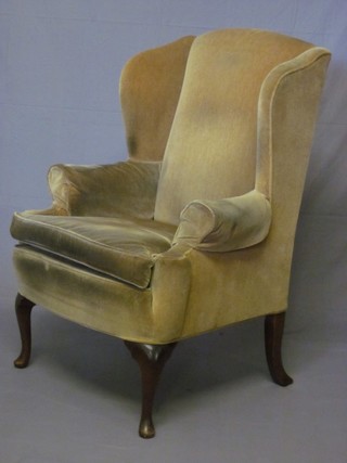 A Georgian style mahogany winged armchair upholstered in yellow material, raised on cabriole supports