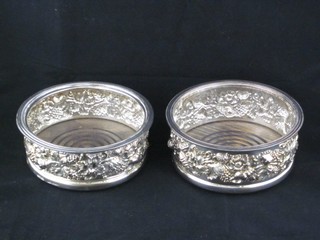 A pair of circular embossed silver plated wine bottle coasters