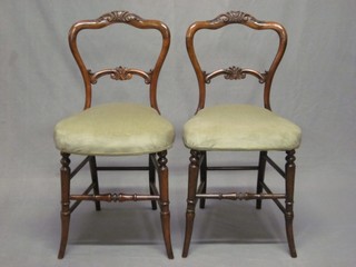 A pair of Victorian carved walnut spoon back bedroom chairs with carved mid rails and upholstered seats, raised on turned supports