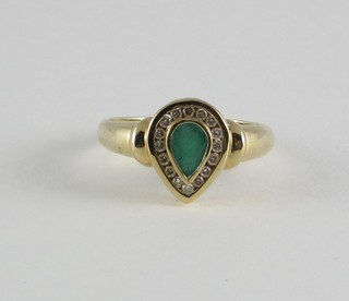 A lady's yellow gold dress ring set a tear drop emerald supported by diamonds