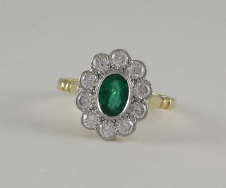 A lady's 18ct yellow gold dress ring set an oval cut emerald surrounded by numerous diamonds, approx 0.70/0.80ct