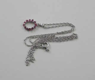 A fine silver chain hung a pendant set red stones