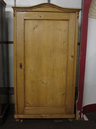 A Continental stripped and polished pine cupboard with arched top, shelved interior and enclosed by a panelled door, raised on bun feet 37"