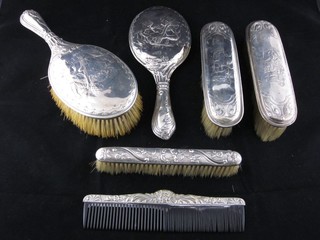 An Edwardian embossed silver 4 piece backed dressing table set comprising pair of hand mirrors and pair of clothes brushes, London 1905 and 1906, together with a silver backed clothes brush and comb