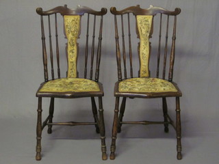 A pair of Edwardian mahogany stick and rail back chairs with upholstered seats, raised on turned supports