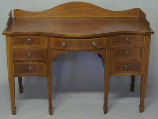 A 19th Century mahogany writing table of serpentine outline  with three-quarter gallery, fitted 1 long drawer flanked by 6 short  drawers, raised on square tapering supports 48"  ILLUSTRATED