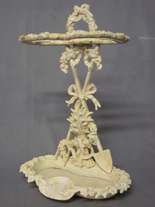 A Victorian style white painted cast iron umbrella stand, decorated gardening trophies