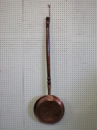 A copper warming pan with turned fruitwood handle