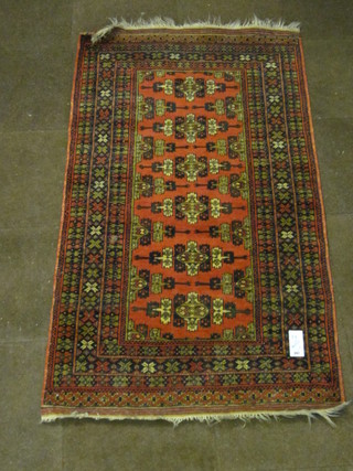 A red ground Afghan rug with geometric decoration to the centre 75" x 40"