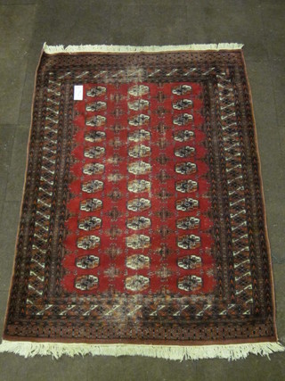 A red ground Bokhara rug with 36 octagons to the centre 72 1/2"  x 51", some wear to the centre