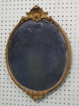 An oval plate mirror contained in a decorative gilt frame 16"