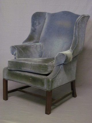 A Georgian style mahogany winged armchair upholstered in blue material raised on square tapering supports
