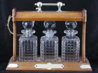 A 3 bottle tantalus contained in an oak and silver plated frame ILLUSTRATED