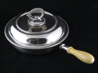A circular silver plated twin section entree dish with turned ivory handle