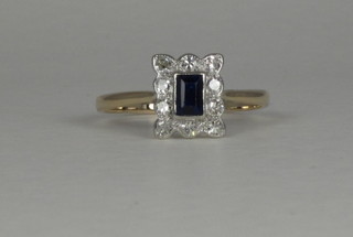A gold dress ring set a square cut sapphire supported by  diamonds