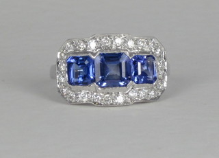 An 18ct white gold dress ring set 3 square cut tanzanites  supported by diamonds, approx 0.50/2.40ct