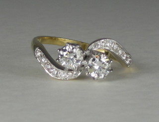A lady's 18ct gold cross-over dress ring set 2 diamonds and with diamonds to the shoulders, approx 0.90ct