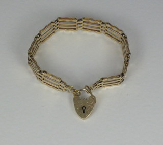 A lady's gold gate bracelet with heart shaped padlock