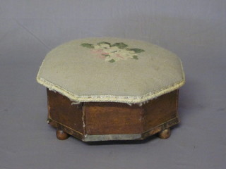 A Victorian octagonal oak foot stool with hinged lid upholstered in Berlin woolwork, raised on bun feet 12"