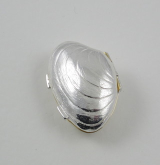 A modern silver pill box in the form of a clam shell