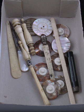 A collection of mother of pearl buttons and ivory handled implements