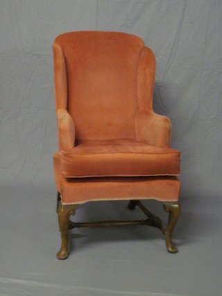 A Queen Anne style walnut framed armchair upholstered in pink Dralon, raised on cabriole supports with turned stretchers