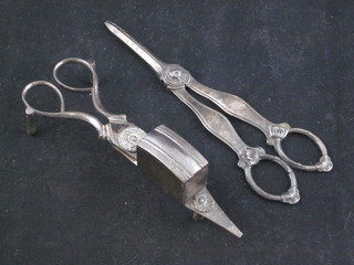 A pair of silver plated grape scissors and a pair of silver plated candle snuffers