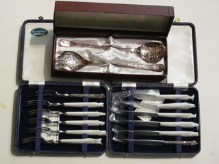 A set of 6 Queens pattern silver handled fruit knives and forks, cased and a pair of silver plated salad servers