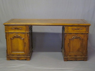 An Eastern carved hardwood kneehole pedestal desk, the pedestals fitted a drawer above a cupboard enclosed by panelled  doors, 63" 