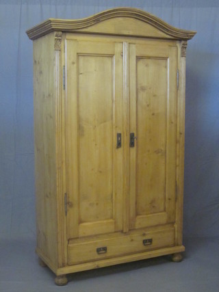 A Continental stripped and polished pine cupboard with arch shaped top, the interior fitted shelves enclosed by panelled doors,  the base fitted 1 long drawer, raised on bun feet 44"