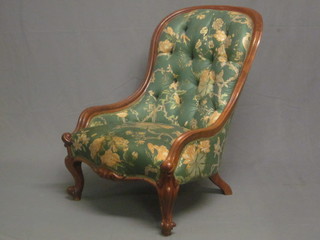 A Victorian mahogany show frame armchair upholstered in green floral material raised on cabriole supports