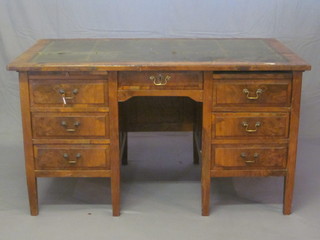 A walnut kneehole pedestal writing desk with inset green leather writing surface, fitted 1 long and 7 short drawers 56"