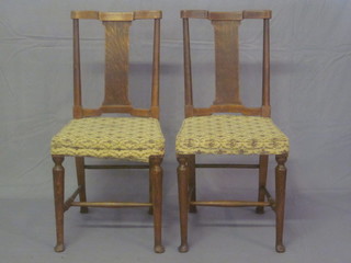 A set of 4 Arts & Crafts oak stick and slat back dining chairs  with upholstered seats, raised on turned supports with H framed  stretcher