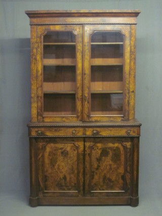 A handsome Victorian inlaid figured walnut bookcase on cabinet with columns to the sides, the upper section with moulded  cornice, the interior fitted adjustable shelves enclosed by glazed  panelled doors, the base fitted 2 long drawers above a double  cupboard enclosed by panelled doors, 49"   ILLUSTRATED