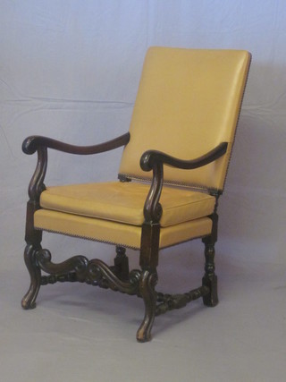 A beech framed Carolean style open arm chair with upholstered leather seat and back, raised on turned and block supports