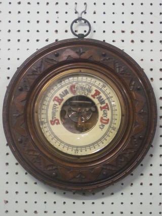 An Edwardian aneroid barometer contained in a carved walnut  case