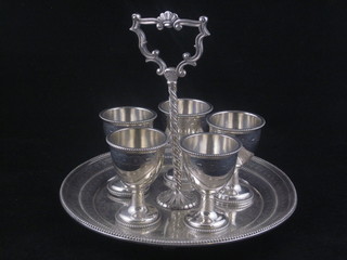 A Victorian silver plated 6 piece egg cruet of circular form, having engraved decoration and raised on 4 bun feet