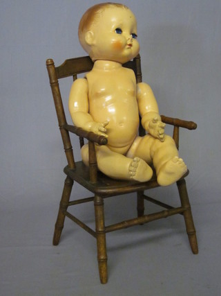A childs high chair together with a plastic doll with articulated limbs
