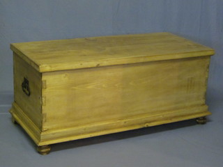 A Continental stripped and polished pine coffer with hinged lid  and iron drop handles, raised on bun feet 45"