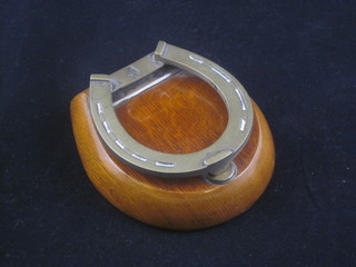 A Victorian oak and silver plated desk paper clip in the form of a horseshoe
