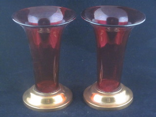 A pair of cranberry glass trumpet shaped vases raised on circular brass spreading feet 6 1/2"