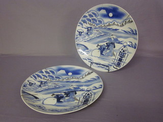 A handsome pair of Oriental blue and white porcelain chargers decorated figures amidst a snow scene 18"