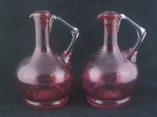 A pair of cranberry glass ewers with clear glass handles 8"