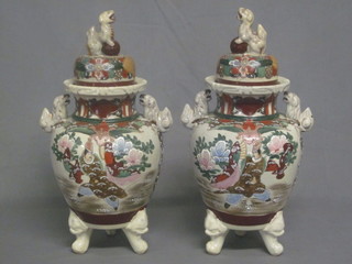 A pair of Japanese late Satsuma pottery twin handled urns and covers, the lids decorated Dogs of Fo 15", f and r,