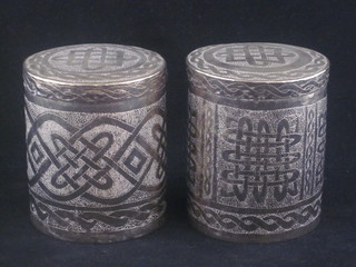 A pair of Eastern engraved white metal cylindrical jars and covers