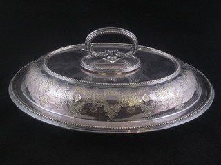 An oval silver plated entree dish and cover with engraved decoration
