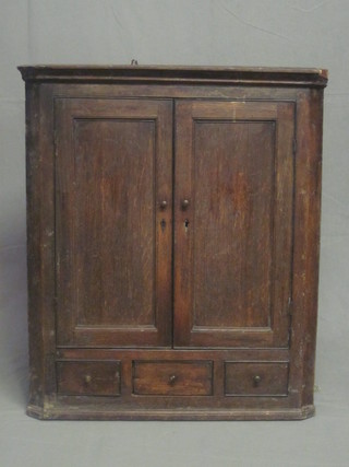 An 18th Century oak hanging corner cabinet with moulded  cornice, the interior fitted shelves enclosed by panelled doors, the  base fitted 1 short drawer flanked by 2 short drawers, 31"