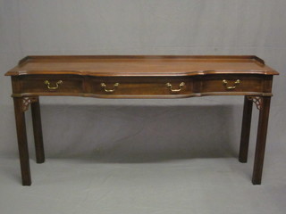 A Georgian style mahogany side table of serpentine outline with three-quarter gallery fitted 1 long drawer flanked by 2 short   drawers, raised on square tapering supports 58"