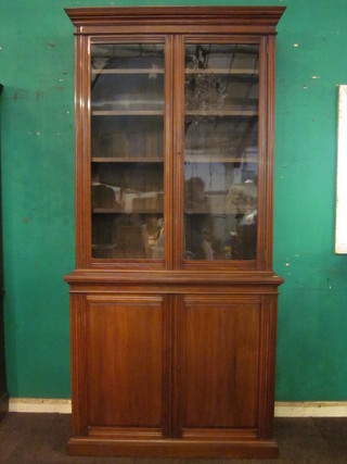 A Victorian walnut bookcase on cabinet, the upper section with moulded cornice, the shelved interior enclosed by glazed panelled  doors, the base fitted a cupboard enclosed by a panelled door,  raised on a platform base 43 1/2"