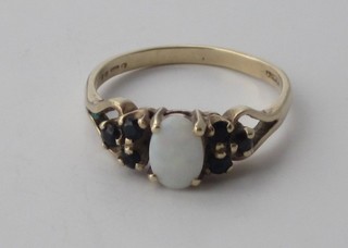 A 9ct gold dress ring set an oval cut opal supported by sapphires